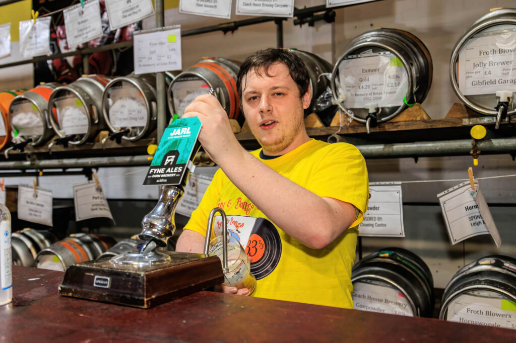 A volunteer in a staff shirt pulls a glass of Jarl at the cask bar at the Bent and Bongs Beer Bash.